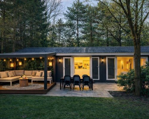 Avondfoto met tuin met sfeerverlichting en zithoek tiny house Veluwe